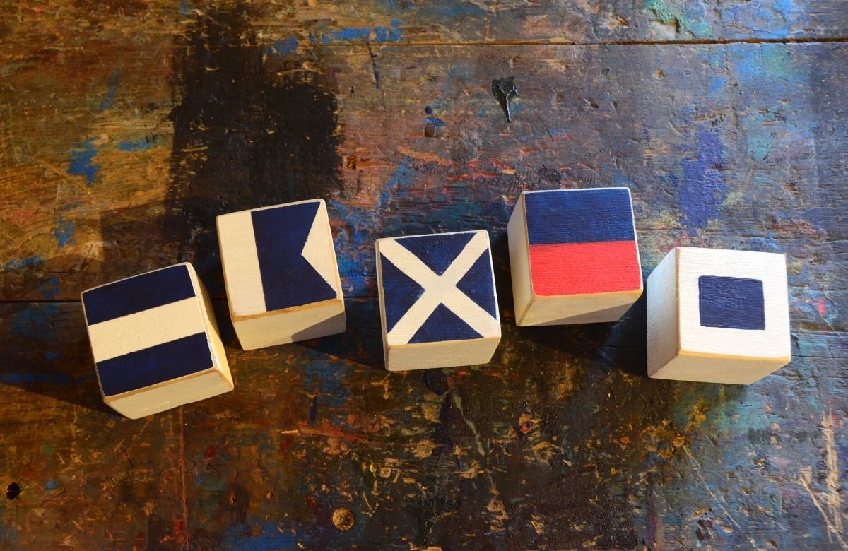 Wooden blocks with nautical flag symbols painted on them. They read: James.