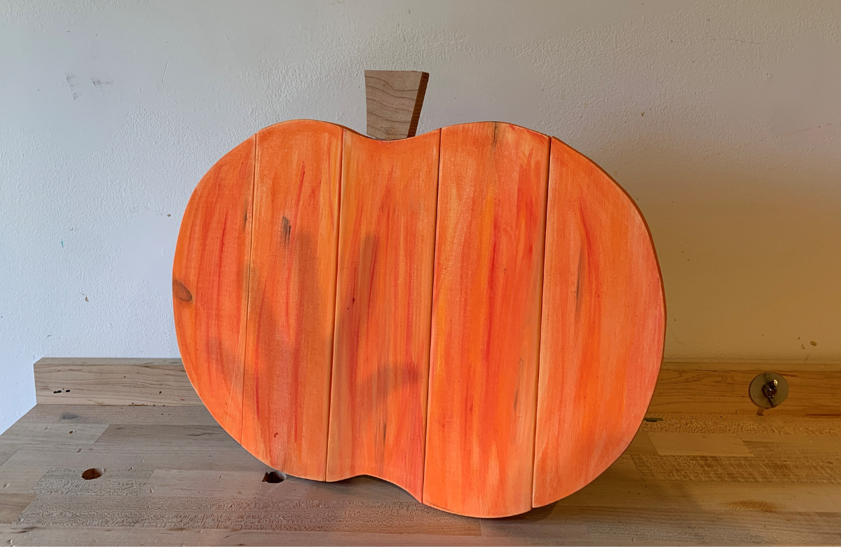 Orange Pumpkin made from Wood with a shadow of a hand on it