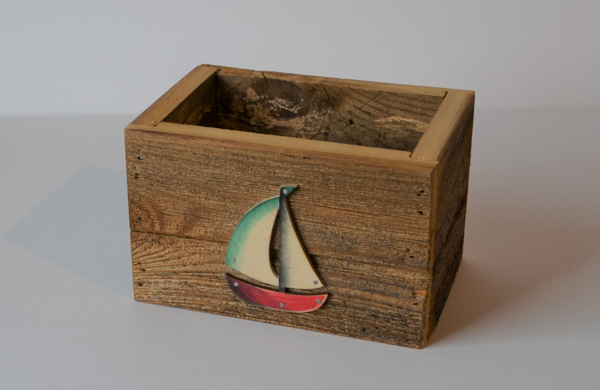 Wooden box with no lid and a sailboat nailed to the front