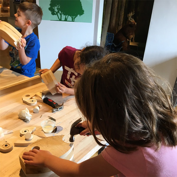 A young museum visitor gladly showing off the Lumberkit she made in the newly created workshop space.